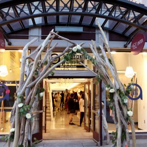 Fabulous driftwood and white flower awning at the entrance to The Arts Center Of The Capital Region in Troy, New York. Through open doors, we see people dressed up for an art opening or a night on the town, going into the main art gallery.